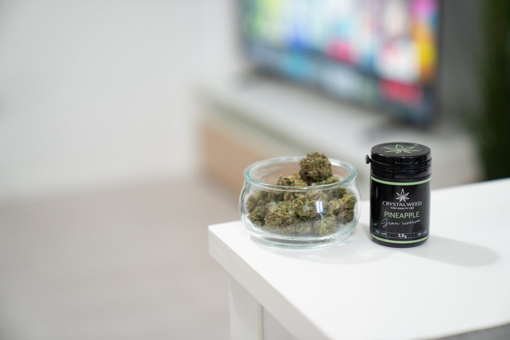 a glass bowl filled with marijuana next to a bottle of marijuana
